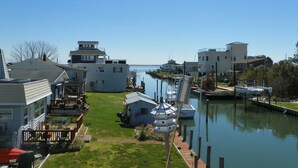 A marina with boats docked, a grassy area, and buildings with a dock.