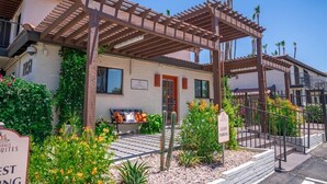 Un edificio con una pergola, un segnale per parcheggio ospiti e una panca con cuscini.