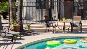 Area piscina con lettini, un tavolo con cuscini e cerchi gonfiabili.