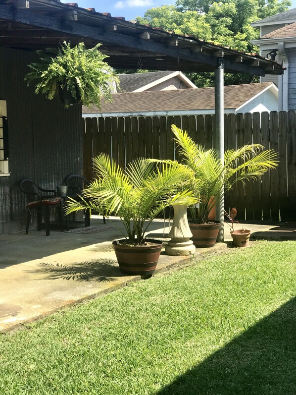 Relax in the serene backyard patio surrounded by lush greenery and a shaded pergola.
