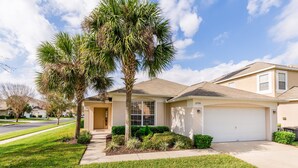 A single-story house with a garage, a well-maintained lawn, and two palm trees.