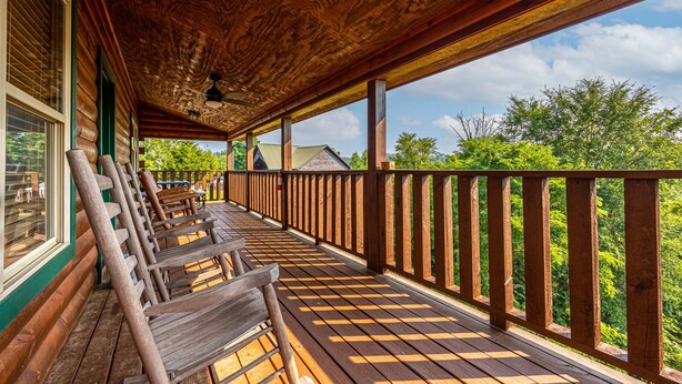 A wooden deck with benches and a railing, overlooking a green landscape. - 3BR Cabin Near Dollywood w/ Hot Tub, Game Room & Mountain Views |  Free ticket (Sevierville)