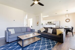 A modern living room with a grey sofa, a wooden coffee table, and a blue patterned rug.