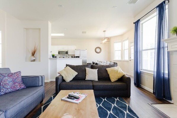 A modern living room with a grey sofa, a coffee table, and a blue patterned sofa.