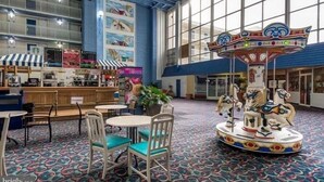 A carousel in a spacious indoor area with tables and chairs, large windows, and a blue ceiling. - Oceanfront and Bay view at the Carousel with indoor pool (ocean city)