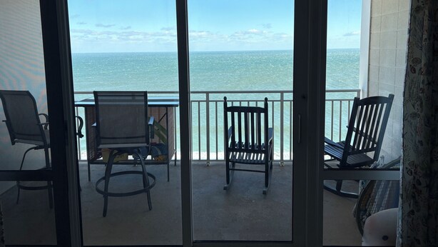 A balcony with two chairs and a table, overlooking a body of water. - Oceanfront and Bay view at the Carousel with indoor pool (ocean city)