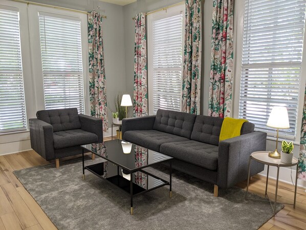 A living room with two grey sofas, a black coffee table, and a small round table with a lamp.