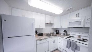 A modern kitchen with white cabinets, a refrigerator, a microwave, a stove, and a sink. - 219 Fully Furnished, WiFi Included! (Scottsdale)