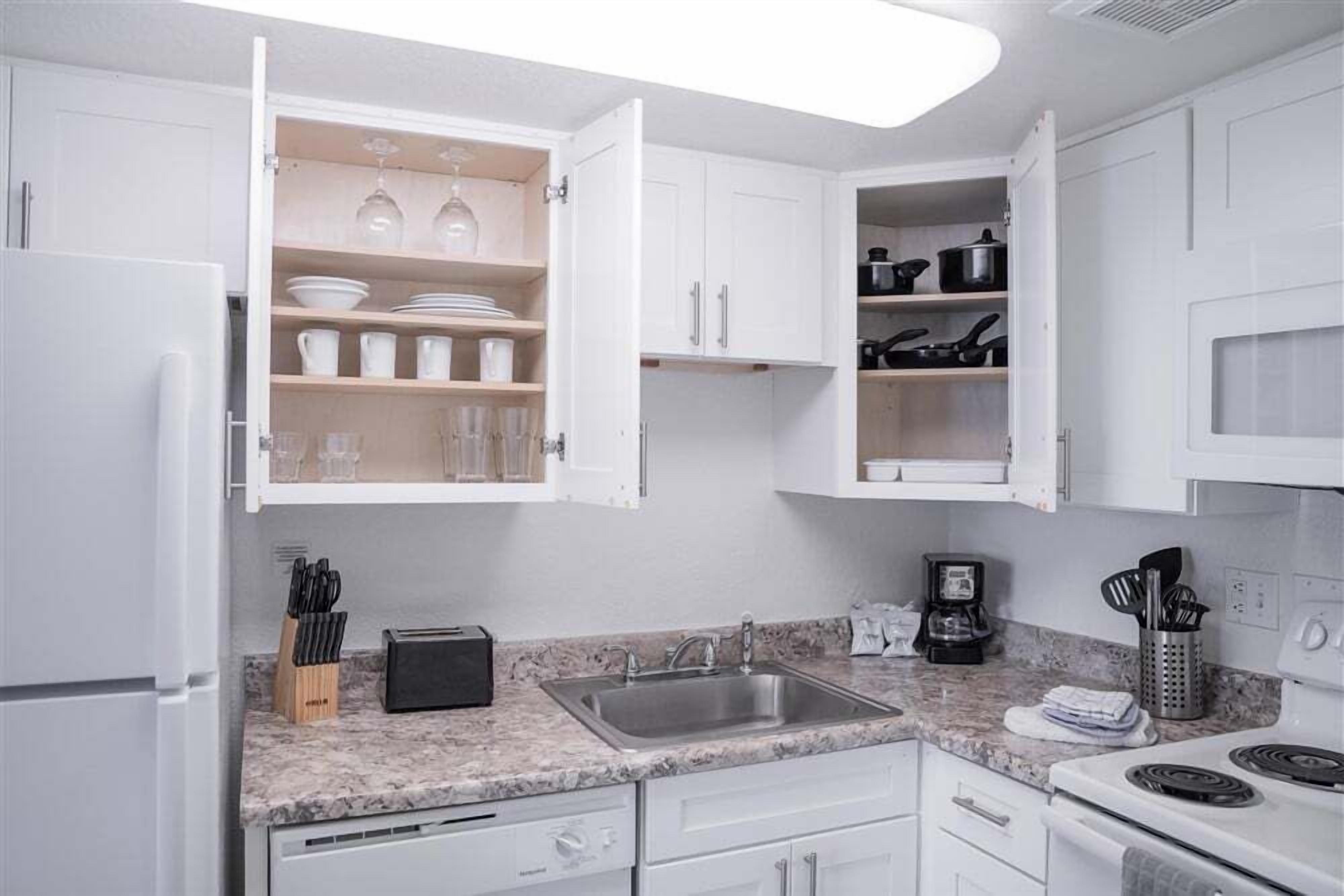 A kitchen with white cabinets, a granite countertop, a sink, and a stove.