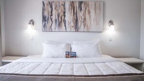 A bed with a quilted cover, two bedside tables, and a wall-mounted abstract painting. - 219 Fully Furnished, WiFi Included! (Scottsdale)
