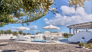 A pool area with lounge chairs and umbrellas, surrounded by a rocky landscape and trees. - La Maison Villa with Large Private Pool - Accommodates 10 (SANTORINI)