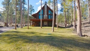 A cabin with a triangular roof, surrounded by tall pine trees.