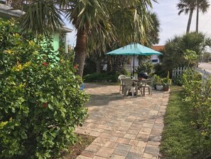 Relax in a serene outdoor space surrounded by lush greenery and a seating area under a shaded umbrella.