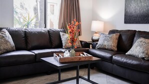Un salon moderne avec un canapé en cuir, une table basse en bois et un vase rempli de fleurs.