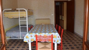 Una habitación pequeña con literas, una mesa y sillas.