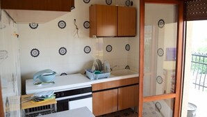 Una cocina compacta con baldosas blancas, armarios de madera y un lavabo.
