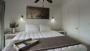 A bedroom with a bed, a ceiling fan, a painting, bedside lamps, a nightstand, and a bedside plant. - 121 Chic Scottsdale Retreat | Heated Pool, Outdoor Lounge & 2 Miles from Old Town! (Scottsdale)