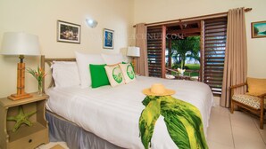 A well-appointed bedroom with a large bed, a nightstand with a starfish decoration, a chair, and a view of the outdoors through a window with wooden shutters. - Villa BEACHNUT - ON PRIVATE BEACH IN A GATED COMMUNITY (Rio Bueno)