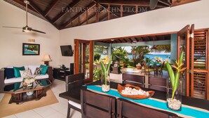 A spacious living area with a dining table, chairs, and a sofa. There are two potted plants on the table, a framed picture on the wall, and a ceiling fan. - Villa BEACHNUT - ON PRIVATE BEACH IN A GATED COMMUNITY (Rio Bueno)