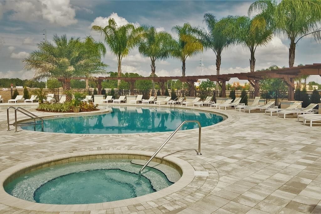 A swimming pool with lounge chairs and palm trees.