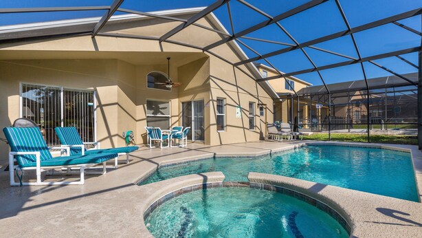 Una piscina con sillas de descanso y un área de patio techada.