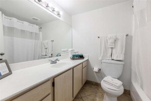 Ein Badezimmer mit Waschbecken, Spiegel, Toilette und Handtuchhalter.