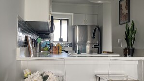 Una cocina moderna con gabinetes blancos, electrodomésticos de acero inoxidable y una barra con taburetes.