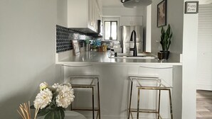 Una cocina moderna con armarios blancos, una isla central y taburetes de bar.