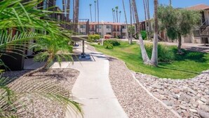 Un camino bordeado de palmeras que conduce a un edificio de varios pisos y balcones.