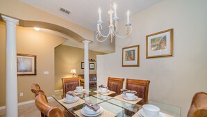 A dining area with a glass table set for six, surrounded by wooden chairs.