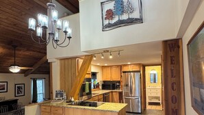 A spacious kitchen with a central island, wooden ceiling, and a 'WELCOME' sign. - A-Frame of Mind in the Smoky's, a mountain retreat. (Whittier)