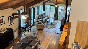 A spacious loft with high ceilings, a dining area, a cozy seating area, and large windows offering views of the outdoors. - A-Frame of Mind in the Smoky's, a mountain retreat. (Whittier)