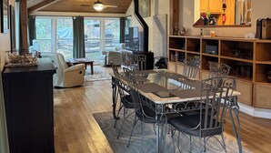 A spacious living area with a wooden ceiling, a dining table with chairs, a sofa, and a kitchen area with wooden cabinets and a built-in stove. - A-Frame of Mind in the Smoky's, a mountain retreat. (Whittier)