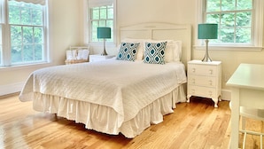 A bedroom with a large bed, two bedside tables, a nightstand, and two windows with white curtains. - Prime East Hampton Village Location. Heated Pool.  Walk To All!  (East Hampton)