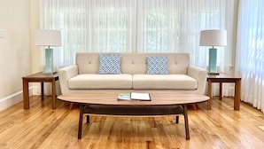 A living room with a beige sofa, two patterned pillows, a wooden coffee table, and two lamps on side tables. - Prime East Hampton Village Location. Heated Pool.  Walk To All!  (East Hampton)