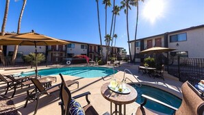 A pool area with lounge chairs, umbrellas, and a small table with drinks. - 120 Living in Ultimate Comfort | Pool, Lounge & Full Kitchen Suite! (Scottsdale)