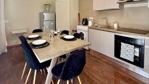 Une cuisine moderne avec un coin repas, comprenant une table dressée pour deux personnes avec des chaises, un lave-linge et un lave-vaisselle.