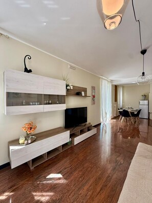 A modern living room with a flat-screen TV, wooden cabinets, and a dining area with a table and chairs. - Holiday Apartment in Puglia for 5 people (Monopoli)