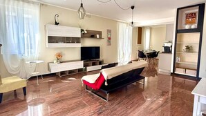Un salon moderne comprenant un canapé, un téléviseur et un coin repas avec une table et des chaises.