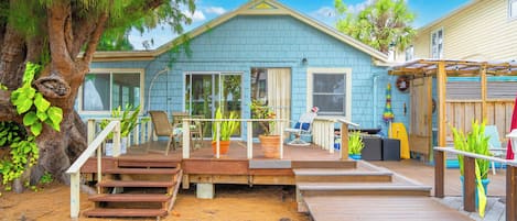 A house with a deck, a tree, and a clear sky.