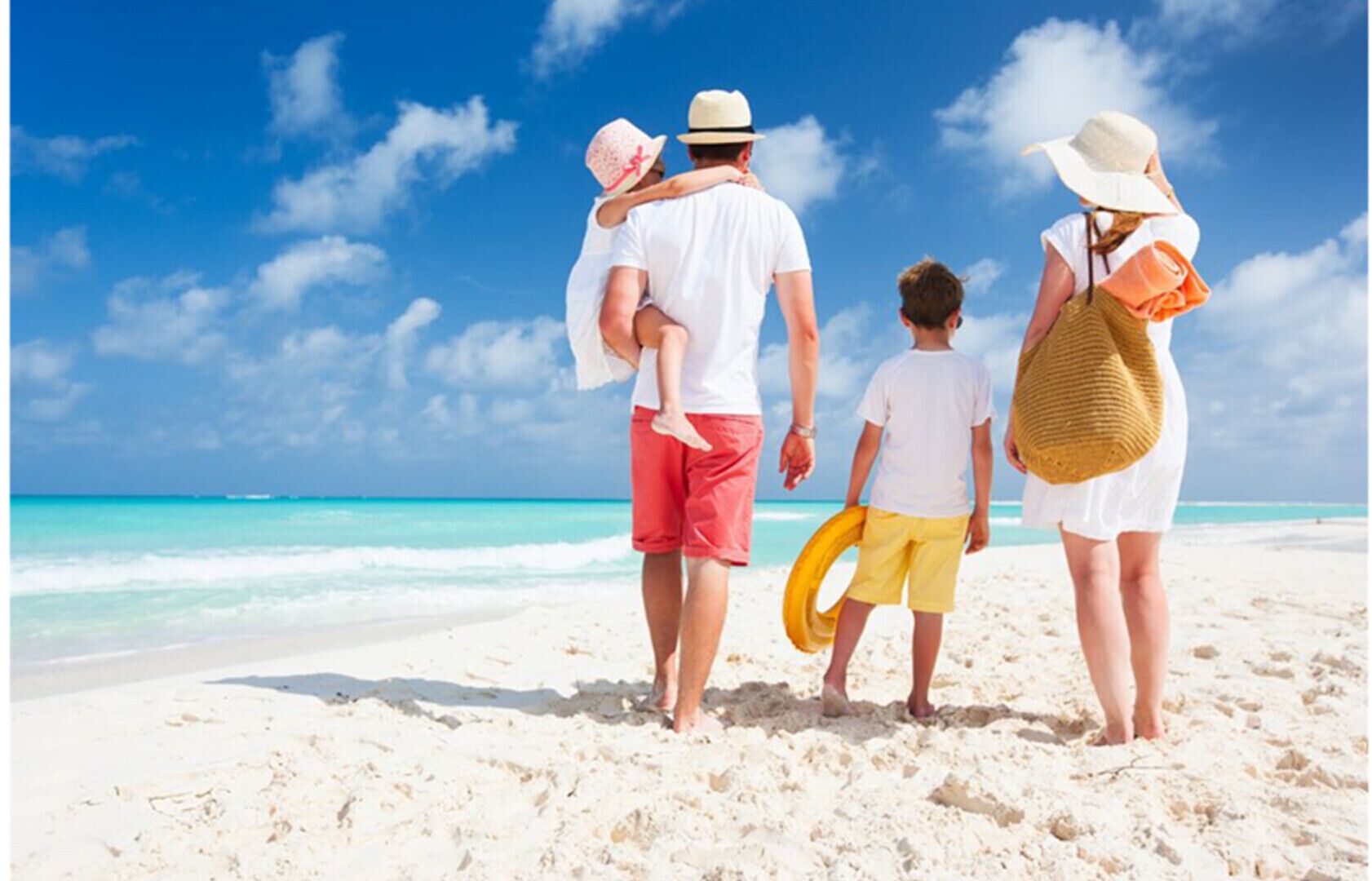 Una familia en una playa arenosa bajo un cielo azul claro.