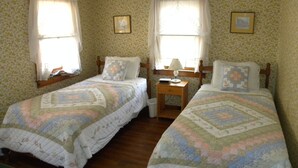 A room with two single beds, floral wallpaper, and a small bedside table with a lamp. - Quaint Cape Cod Cottage close to all nantucket sound beaches, and RT28 Fun  (South Yarmouth)