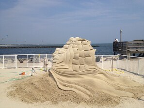A sandy beach with a large sand sculpture of a dragon.