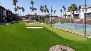 Ein Golfplatz mit Putting Green, Palmen und Wohnhäusern im Hintergrund.