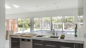 A modern kitchen with a central island, large windows, and recessed ceiling lights. - Private Westhampton Escape 5BR, Pool, Hot Tub, Near Beach (Westhampton)