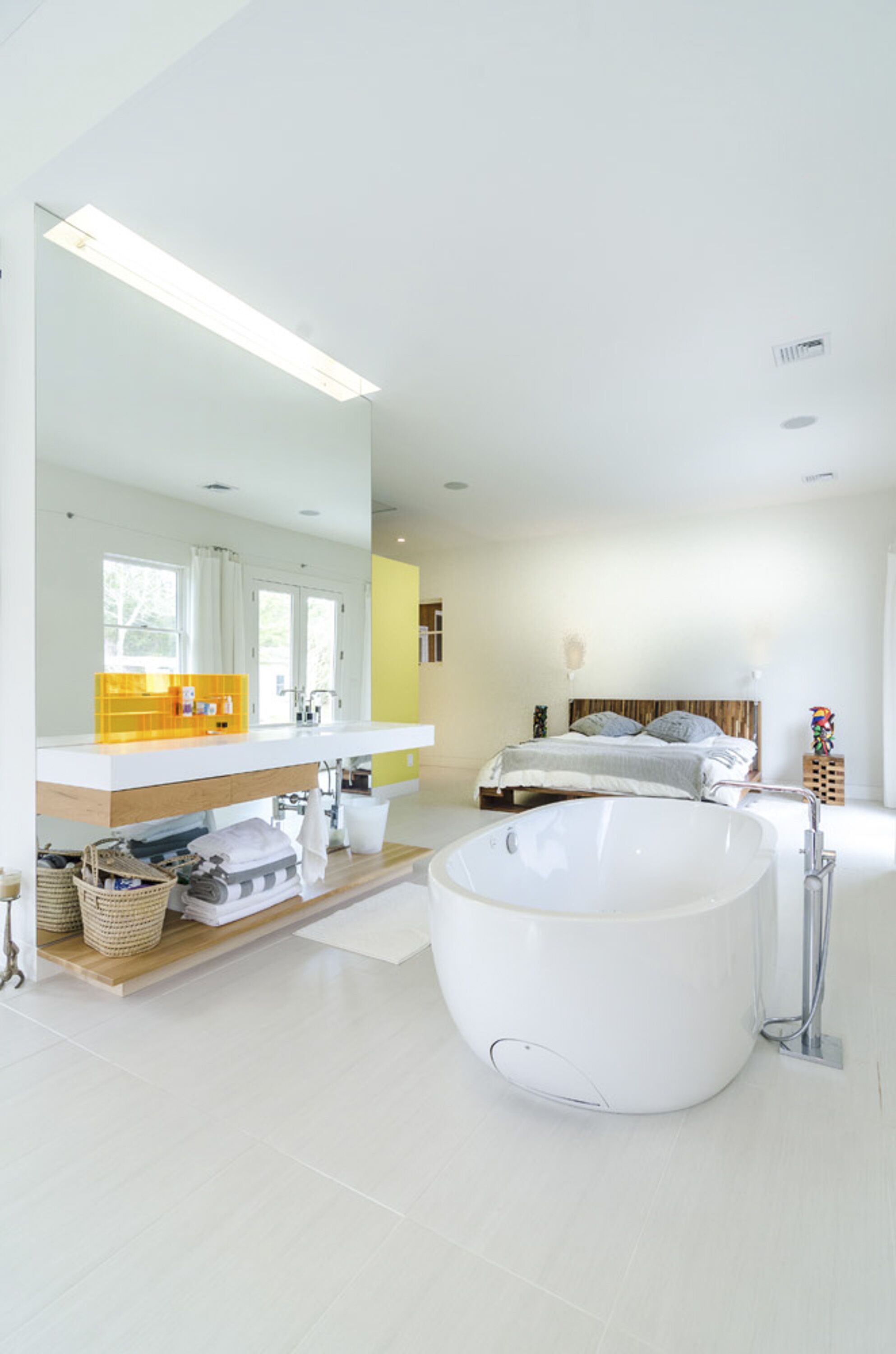 A modern bathroom with a large bathtub, a double sink vanity, and a large mirror.