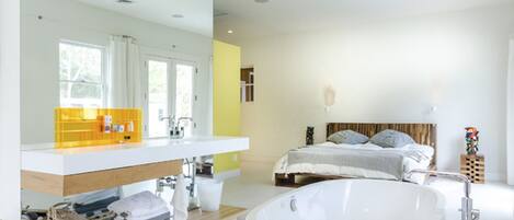A modern bathroom with a large bathtub, a double sink vanity, and a large mirror.