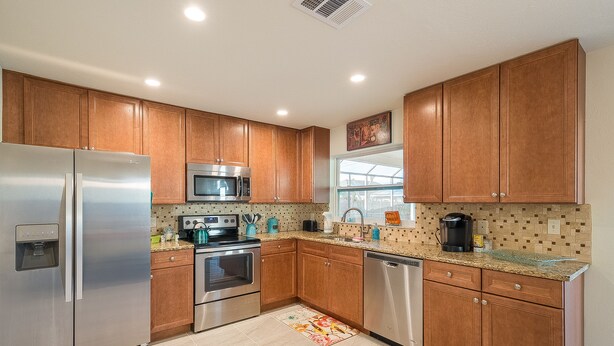 A modern kitchen with wooden cabinets, stainless steel appliances, and a window providing natural light. - ★Private 5 Star Pool Home: 5 min to Beach★ (Naples)