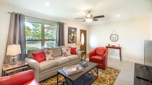 A living room with a sofa, red chair, coffee table, and a TV. - ★Private 5 Star Pool Home: 5 min to Beach★ (Naples)