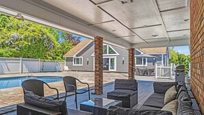 A covered outdoor area with a pool, outdoor furniture, and a brick wall. - Southampton 4BR Home | Pool, Game Room (Southampton)